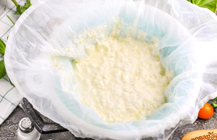 1. Этап. Адыгейский сыр рецепт в домашних условиях из молока и уксуса: Застелите дуршлаг двойным слоем марли или специальной пленкой для сыра. Аккуратно перелейте в нее всю жидкость из емкости. Сыр останется в дуршлаге, а сыворотка — стечет. Кстати, на сыворотке можно приготовить вкусные блины. Подвесьте сыр на 1-1,5 часа, чтобы из него стекла сыворотка и вмешайте в массу соль.