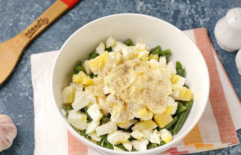 1. Этап. Салат из зеленой фасоли с яйцами: Заправьте салат майонезом, выдавите зубчик чеснока, посолите и поперчите по вкусу.