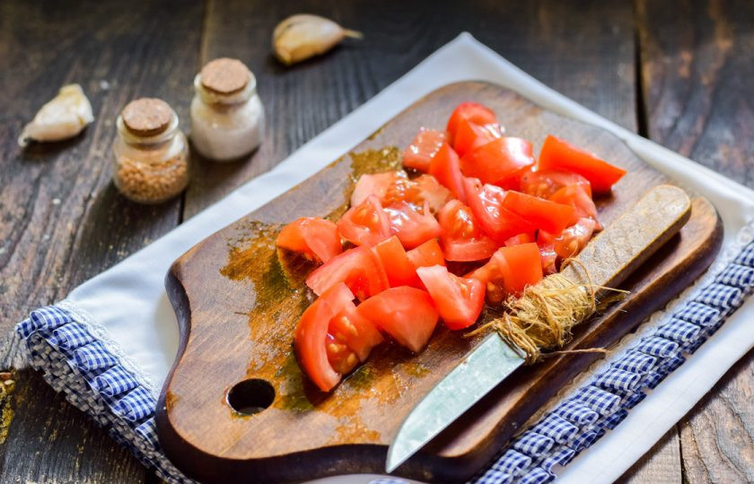 1. Этап. Салат Пеструшка с курицей: Помидор сполосните и просушите, нарежьте небольшими кубиками.