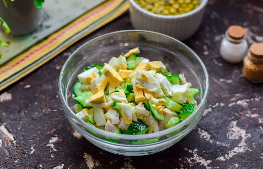 1. Этап. Салат с огурцом и горошком: Куриное яйцо очистите и нарежьте небольшими кусочками, переложите в общую емкость.