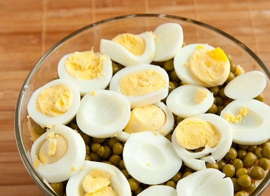 1. Этап. Салат типа Оливье: Яйца отварите вкрутую. Очистите их и нарежьте кружками сверху на горох.