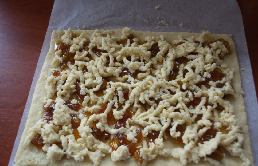 1. Этап. Печенье на кефире с вареньем: Вторую часть теста натрите на терке и выложите на варенье натертую крошку.