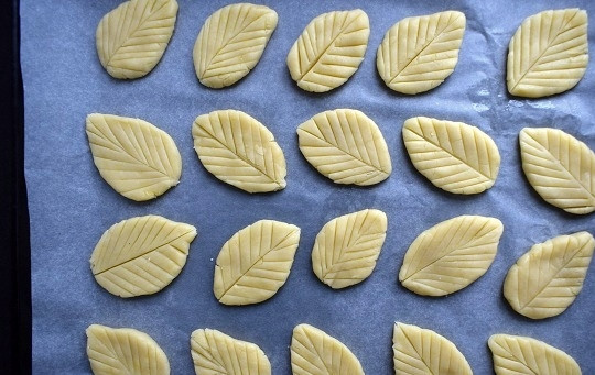 1. Этап. Печенье Весенние листья: Отщипните от теста кусочки, скатайте в шарики, размером с грецкий орех, по весу примерно по 15 г. Каждый шарик приплюсните на ладони, сформируйте листик. С помощью ножа сделайте неглубокие надрезы, имитируя прожилки листочка.
