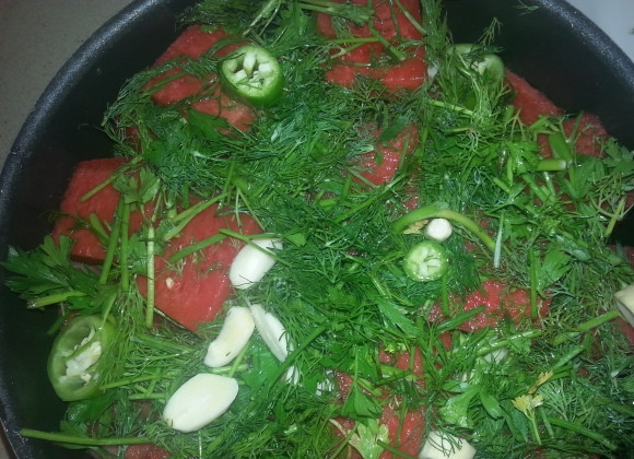 1. Этап. Маринованные арбузы в банках: Петрушку,укроп, перец и хрен измелчите. Чеснок нарезать не нужно. В кастрюлю начинайте укладывать зелень, хрен и чеснок слоями, чередуя с кусочками арбуза.