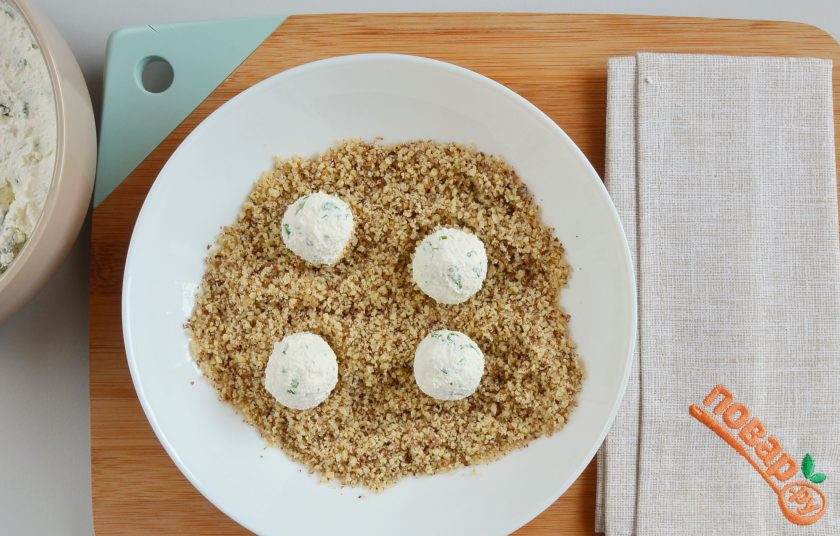 1. Этап. Закуска под коньяк: Чайной ложкой наберите сырную массу и скатайте в шарики, обваляйте в молотых грецких орехах.