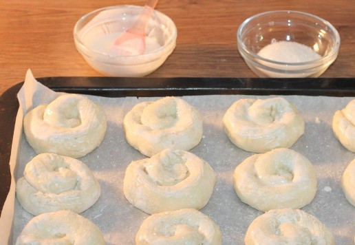 1. Этап. Творожное печенье с виноградом кишмиш: 13. Застилаем противень пекарской бумагой и смазываем ее холодным сливочным маслом. Раскладываем на противне заготовки печенья и смазываем жидкой сметаной (1 ст. л. сметаны+1 ст. л. воды). Если виноград немного кисловатый, можно посыпать каждую печенюшку сахаром ( по 1 щепотке).