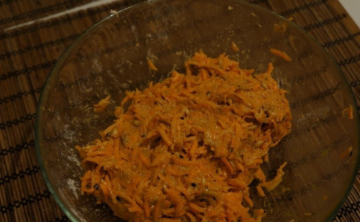 1. Этап. Драники из моркови: 2. Подготовьте емкость для фарша. Выложите морковь в емкость. Всыпьте зерна пророщенной пшеницы. Добавьте ржаную обдирную муку, кунжут. Посолите. В емкость добавьте яйцо. Все положенные ингредиенты перемешайте. Должна получиться условно однородная масса.