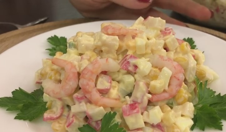 1. Этап. Салат с крабовыми палочками, с креветками и свежим огурцом: 7. Красиво выложите порцию салата на тарелку, добавьте по краям зелень, а сверху положите креветочки. Приятного аппетита!