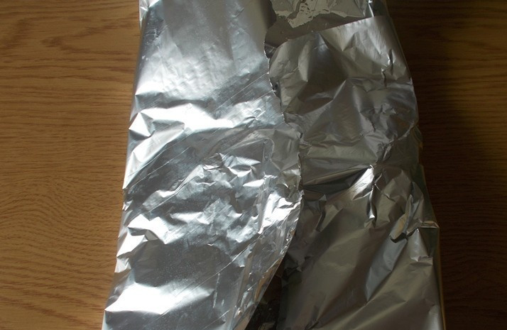 1. Этап. Кролик в фольге в духовке: Сбрызгиваем мясо растительным маслом и плотно заворачиваем крольчатину в фольгу.