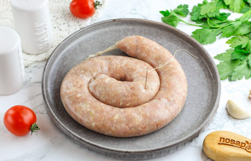 1. Этап. Домашняя варено-копченая колбаса: Тщательно промойте череву изнутри и снаружи. Завяжите ее конец нитью и проколите иглой в нескольких местах. Наполните череву фаршем, аккуратно фаршируя ее, чтобы она не порвалась. Места скопления воздуха между фаршем прокалывайте иглой. Набивайте не плотно, чтобы колбаса не лопнула при варке. Конец снова завяжите нитью.