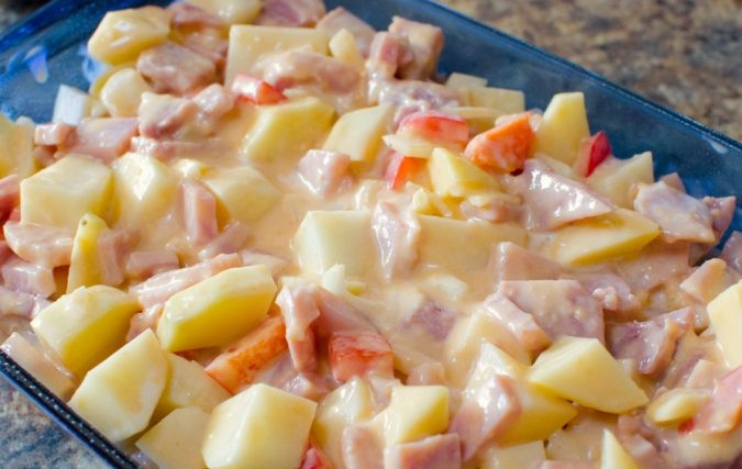 1. Этап. Запеканка из картофеля, ветчины и сыра: Нарежьте небольшими кусочками лук, картофель, перец и ветчину. Выложите ингредиенты в форму для выпечки. Добавьте заливку.