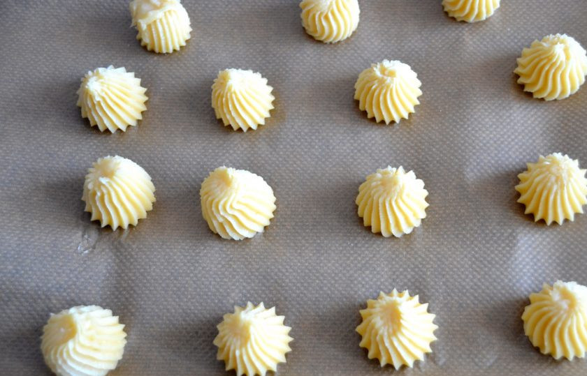 1. Этап. Картофельные профитроли: Переложите картофельное тесто в мешок и отсадите на лист для выпечки. Разогрейте духовку до 200 градусов.