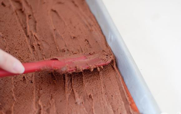 1. Этап. Шоколадные сэндвичи с начинкой из мороженого: 1. Сделать мороженое. Выложить нарезанный белый шоколад в большую миску, установить сверху сито с тонкой сеткой. Нагреть молоко, сахар и соль в средней кастрюле на среднем огне, время от времени помешивая. Взбить желтки в миске. Медленно влить теплую молочную смесь в желтки и взбить венчиком. Вылить яичную смесь обратно в кастрюлю. Увеличить огонь и варить, постоянно помешивая резиновым шпателем. Готовить, пока смесь не сгустилась. Вылить смесь через сито поверх шоколада. Размешивать до тех пор, пока шоколад не растает, и смесь не будет однородной. Перемешать со сливками. Если необходимо, перемешать смесь на ледяной бане, пока она не остынет. Накрыть крышкой и поставить в холодильник на несколько часов или на ночь. Выложить смесь в машину для мороженого и заморозить в соответствии с инструкцией. Разогреть духовку до 175 градусов. Выстелить противень пергаментной бумагой или силиконовым ковриком. В большой миске миксером взбить масло с сахаром до однородной массы. Добавить яйцо и ванильный экстракт, продолжая взбивать. В небольшой миске перемешать муку, какао-порошок и соль. Добавить мучную смесь в сливочную смесь и тщательно перемешать. Вылить тесто на подготовленный противень. Используя резиновый шпатель, равномерно распределить тесто по всей поверхности. Тесто должно касаться всех сторон и углов.