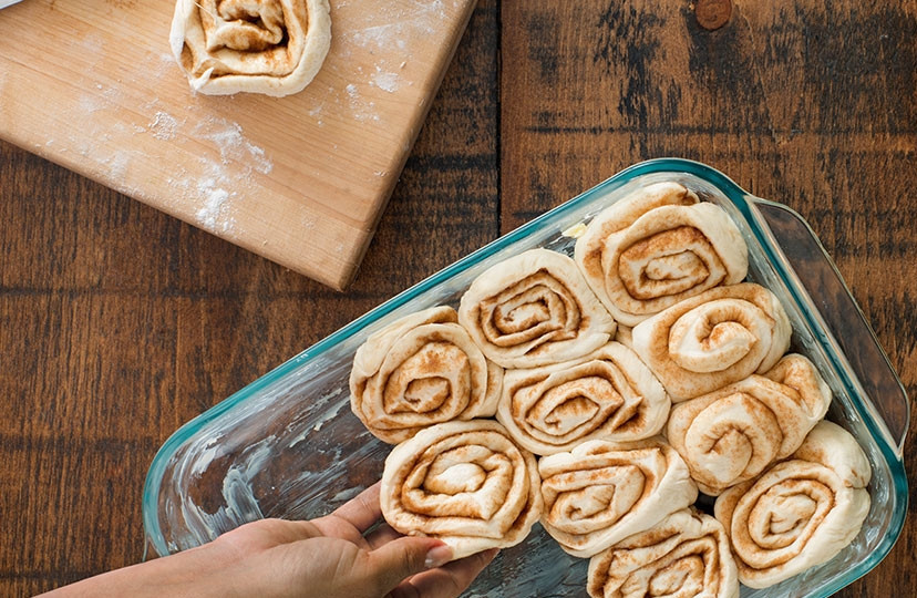 1. Этап. Улитка с корицей (оригинальный рецепт): Форму для выпекания смазываем сливочным маслом. Укладываем в форму булочки, накрываем полотенцем и оставляем на 20 минут.