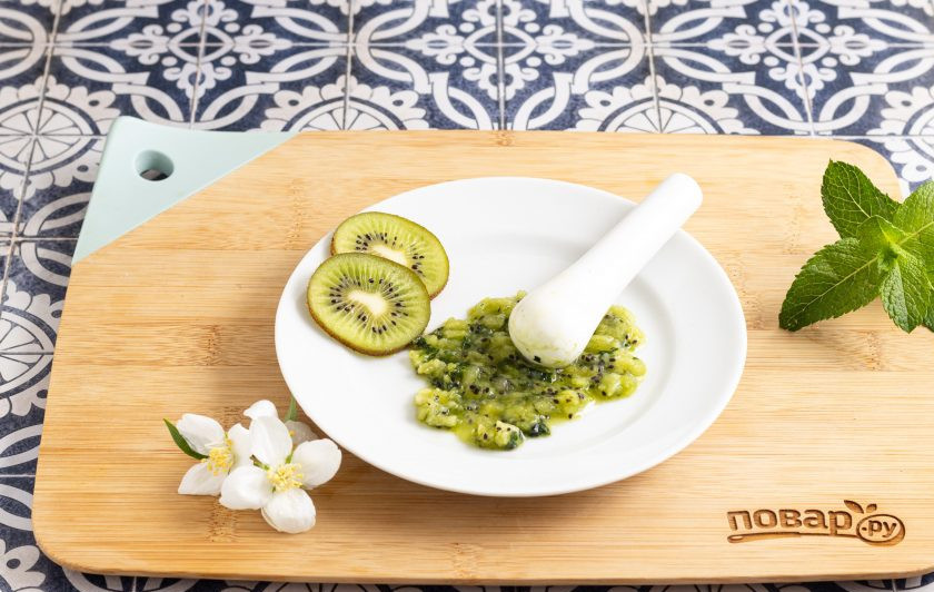 1. Этап. Моктейль: Половинку киви очистите от кожуры и порежьте на кубике. Добавьте к нему листья мяты и подавите до однородного пюре барным мадлером или толкушкой.