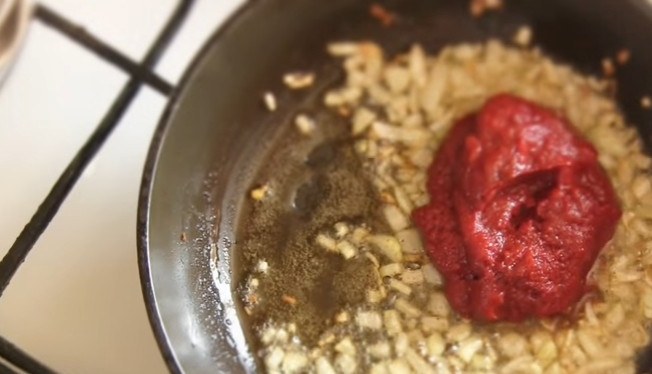 1. Этап. Солянка сборная мясная с колбасой: 5. На смеси сливочного и растительного масла обжарьте лук, затем добавьте томатную пасту, немного воды и дайте закипеть.