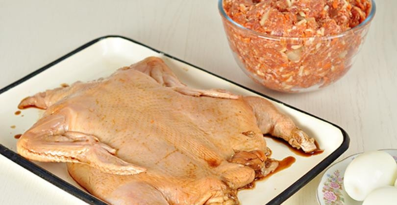 1. Этап. Курица с яйцом: Лук натрите на мелкой терке, морковь — на крупной, сыр — на крупной, ананасы порубите кубиками. Все ингредиенты для начинки смешайте в миске. Шею курицы завяжите, а через низ выложите половину начинки, затем 3 отварных яйца подряд, далее — начинку. (не забудьте про ножки). Затем зашейте карман, ножки скрестите и завяжите.