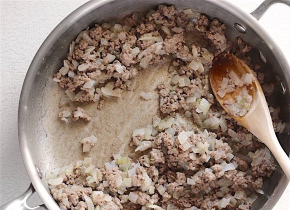1. Этап. Ракушки с фаршем в томатном соусе: 2. Обжаривайте содержимое сковороды до готовности фарша с луком, затем насыпьте муку.
