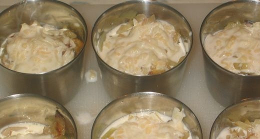 1. Этап. Жульен с курицей и белыми грибами: Отварную курицу нарежьте и выложите на лук. В отдельной пиалочке смешайте сливки и плавленый сыр, доведя их до однородности. Полученным соусом залейте содержимое кокотниц.