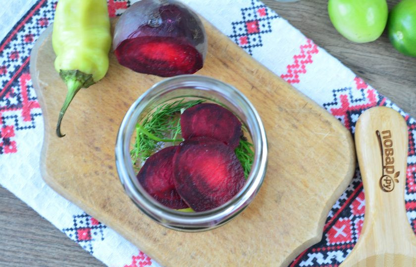 1. Этап. Зеленые помидоры со свеклой на зиму: Почистите свеклу, нарежьте кружками. На дно банок выложите по 2-3 ломтика свеклы.