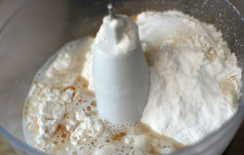 1. Этап. Лепешки на сковороде с зеленым луком: 1. Добавьте в чашу кухонного комбайна муку, соль, рапсовое масло, 1 чайную ложку кунжутного масла. Влейте горячую воду и смешайте.