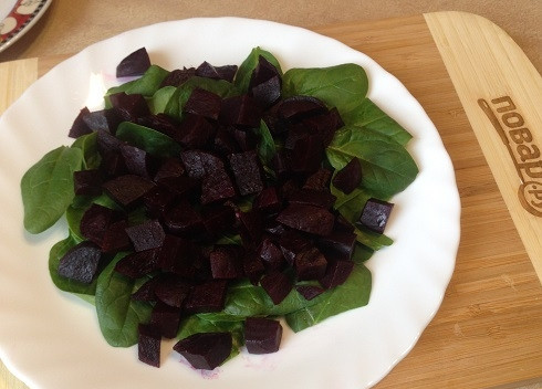 1. Этап. Салат из свеклы с яблоками и шпинатом: 2. Заранее отваренную и охлажденную свеклу очистим и нарежем небольшими кубиками. Выложим на шпинат.