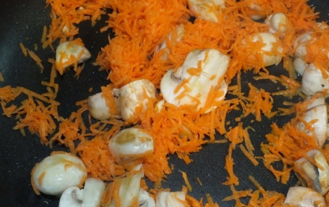 1. Этап. Шампиньоны тушеные с овощами: Морковь натрите и добавьте к грибам. Обжаривайте еще пару минут.