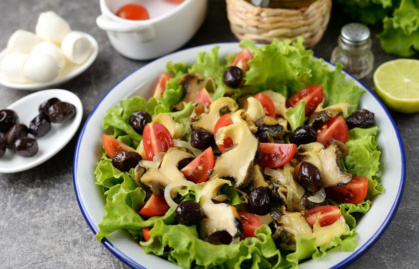 1. Этап. Салат с рапанами: Нарежьте помидоры черри четвертинками, выложите их на салат, добавьте маслины.