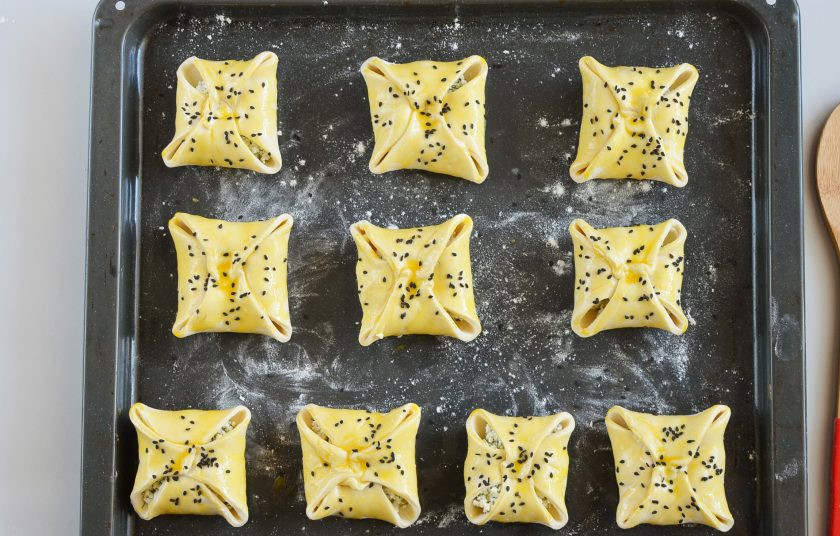 1. Этап. Слоеные конвертики с творогом: Поместите конвертики на противень, можно притрусить мукой или смазать маслом лист предварительно. Смажьте желтком, притрусите кунжутом. Отправьте в духовку на 20 минут.