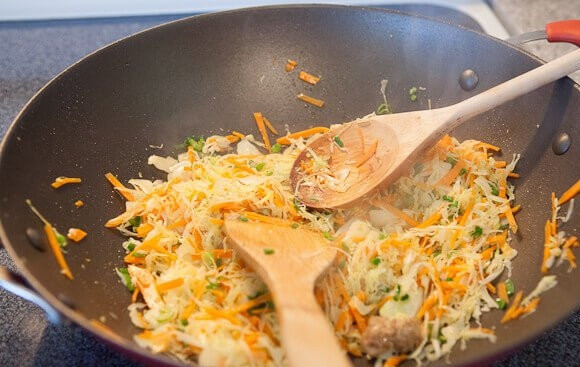 1. Этап. Спринг роллы с курицей: 6. Обжаренный фарш снимите со сковороды, добавьте туда еще немного масла. Выложите измельченный чеснок и имбирь, обжарьте их пару минут, а затем добавьте капусту с морковью. Жарьте немного овощи до мягкости.