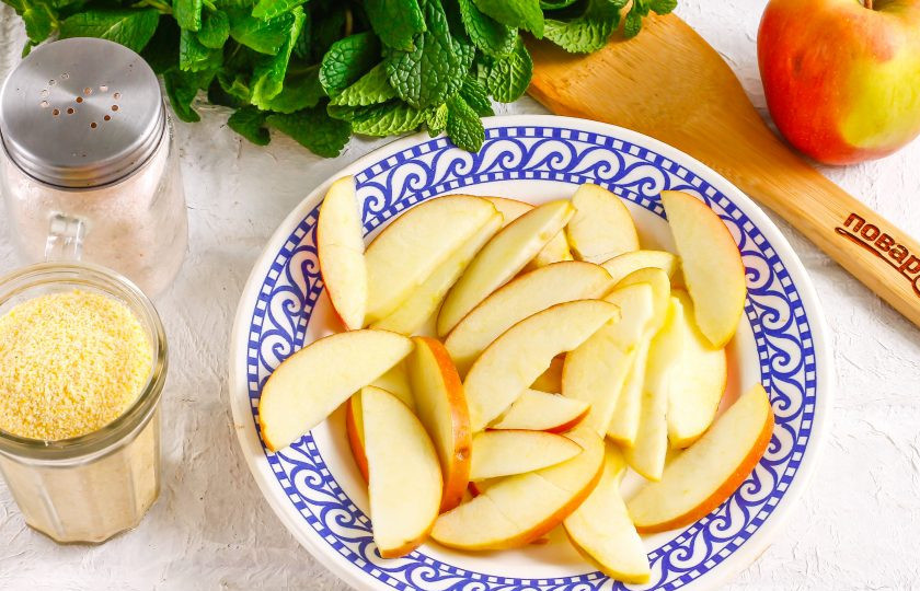 1. Этап. Шарлотка из кукурузной муки: В это время прогрейте духовку до 180 градусов. Промойте яблоко в воде, располовиньте, удалите семена и промойте. Если плод крупный, то используйте один, если мелкий, то два. Нарежьте тонкими ломтиками. Именно тонкими, так как тяжелые кусочки фруктов не будут давать выпечке расти вверх.