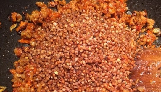 1. Этап. Гречка по-купечески с фаршем: Добавьте к овощам и мясу промытую гречневую крупу. Тщательно перемешайте все ингредиенты на сковородке, сделайте огонь самым минимальным.