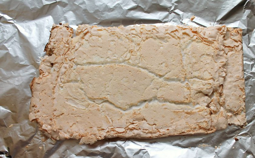 1. Этап. Меренговый рулет с клюквой: Противень с меренговым тестом поставьте в горячую духовку и выпекайте при температуре 160 градусов в течение примерно 25 минут, до румяного цвета. Пласт должен уплотниться и не липнуть к пальцам, если дотронуться. Переверните готовый меренговый пласт на другой кусок пергамента или фольги, дайте немного полежать и аккуратно снимите бумагу со дна. Оставьте пласт до полного остывания.