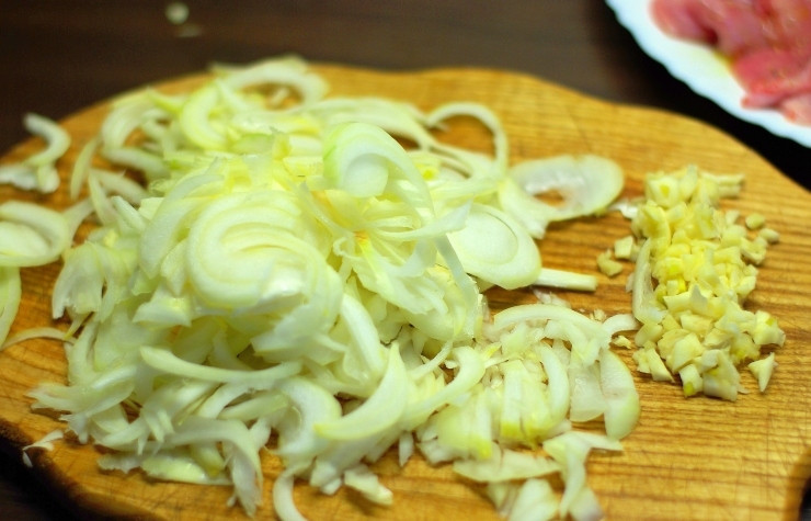 1. Этап. Тушеные ножки кролика: Мелко рубим чеснок и нарезаем тонкими полукольцами лук.