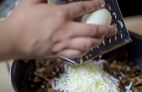 1. Этап. Куриный салат с грибами: 5. Жареные грибочки соедините с тертым на средней терке белком. Тщательно перемешайте, добавьте щепотку перца по вкусу.