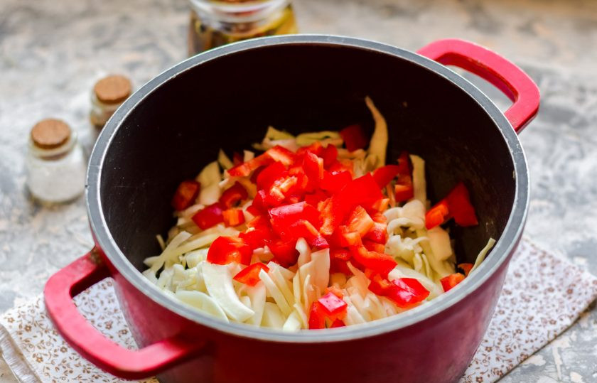 1. Этап. Простой салат из капусты на зиму: В кастрюле доведите до кипения воду, переложите капусту, добавьте нарезанный кубиками перец.