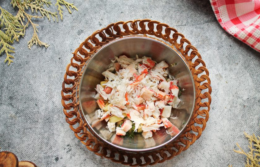 1. Этап. Салат с крабом и персиками: Крабовое мясо порежьте и выложите в салат.