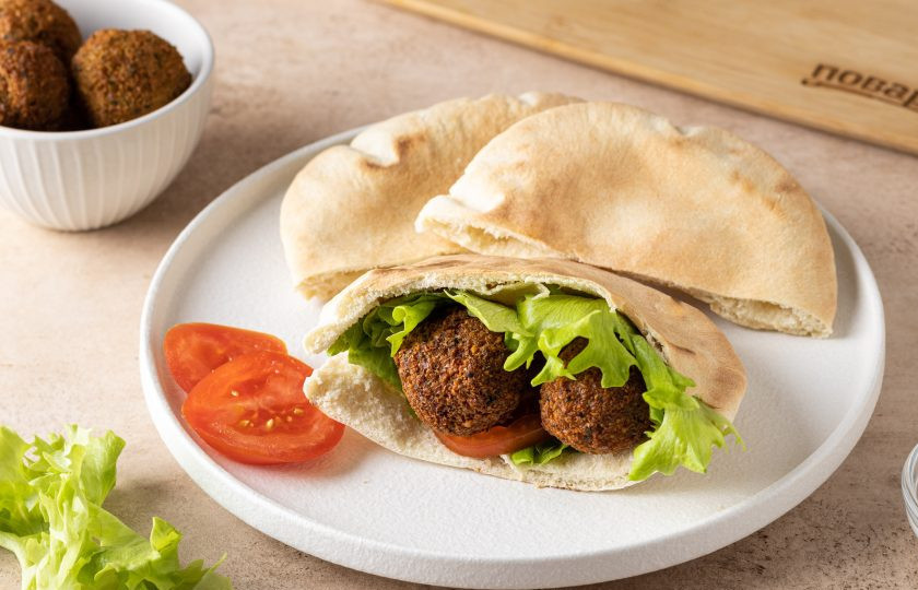 1. Этап. Фалафель в пите с салатом и помидором: Выложите в питу несколько кружочков помидора, пару листочков салата и шарики фалафеля. Сверху полейте соусом.