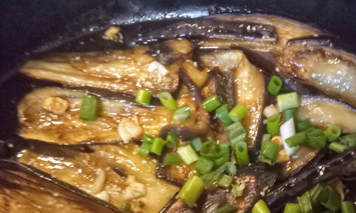 1. Этап. Баклажаны в соевом соусе и кунжуте: В сковороде на огне чуть ниже среднего разогреть оставшееся кунжутное масло, добавить имбирь, чеснок и перец красный жгучий. Готовить 2 минуты. Добавить зелёный лук. Жарить ещё минуту. Затем смешать с соевой заправкой и убрать с огня. Наконец, полить баклажаны полученной смесью до полного покрытия и отправить их в духовку ещё на 10 минут.