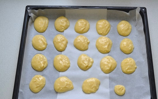 1. Этап. Профитроли с красной икрой: 8. Подготовьте стакан с водой. Окуните ложку в воду, после возьмите тесто и выложите на противень. Снова ложку в воду и так до тех пор, пока тесто не закончится. Отправьте противень в разогретую до 190 градусов духовку.