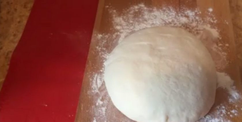 1. Этап. Пицца с беконом и ананасом (Гавайская): 4. Повторите растягивание по кругу, после чего переверните тесто, выровняйте его поверхность и оставьте под пленкой до конца расстойки. Выложите тесто на присыпанную мукой рабочую поверхность, соберите края к середине, переверните и накройте крышкой.