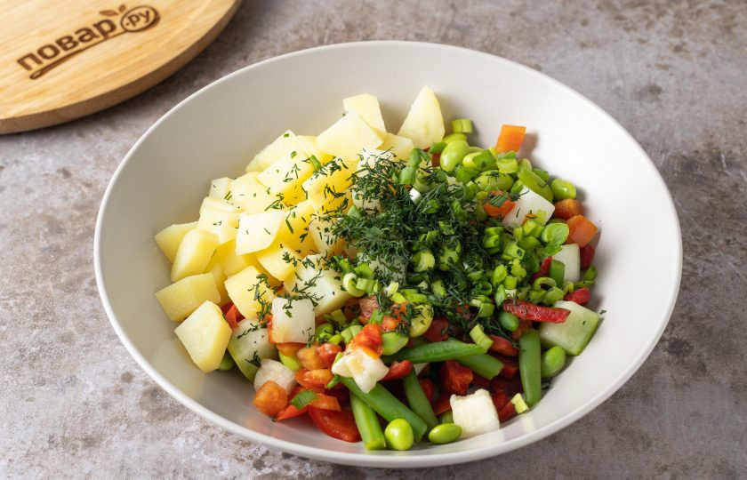 1. Этап. Cалат из замороженных овощей: В глубокую миску переложите картофель, замороженную овощную смесь. Добавьте мелко порубленную зелень.