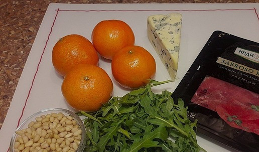 1. Этап. Новогодний салат мандариновый с сыровяленой индейкой: Для приготовления салата понадобятся: - индейка бедра сыровяленая, - мандарины, - сыр с голубой плесенью, - руккола, - орешки кедровые