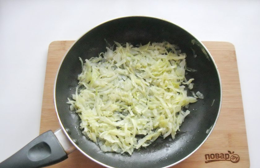 1. Этап. Пирог с белой рыбой: Налейте подсолнечное масло и немного воды. Накройте сковороду крышкой и тушите капусту с луком на среднем огне, перемешивая до готовности.