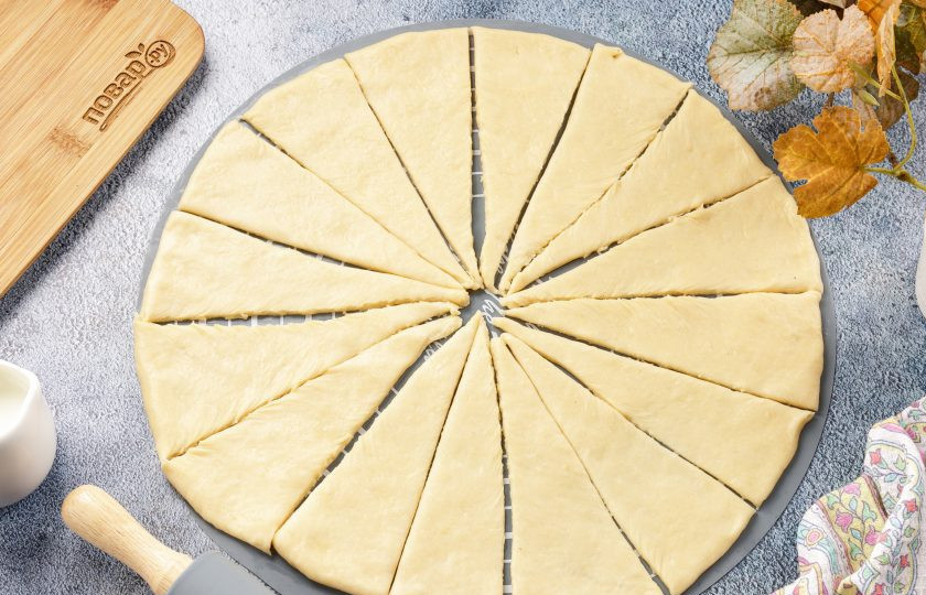 1. Этап. Пальчики дрожжевые: Разделите тесто на две части. Каждую раскатайте в круг, диаметром не более 30 см. Разрежьте на сегменты, как пиццу. Чем уже получатся кусочки, тем меньше будут рогалики. Если хотите покрупнее, то режьте на меньшее число, чем у меня.