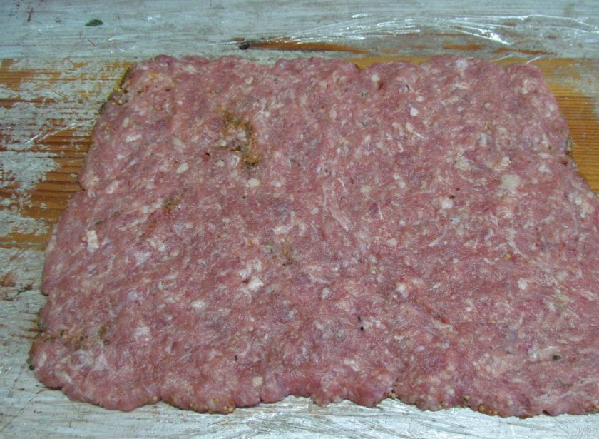 1. Этап. Праздничный мясной рулет: На специи выложите тонким слоем свиной фарш, лучше это делать мокрыми руками. Сформируйте ровный прямоугольник.