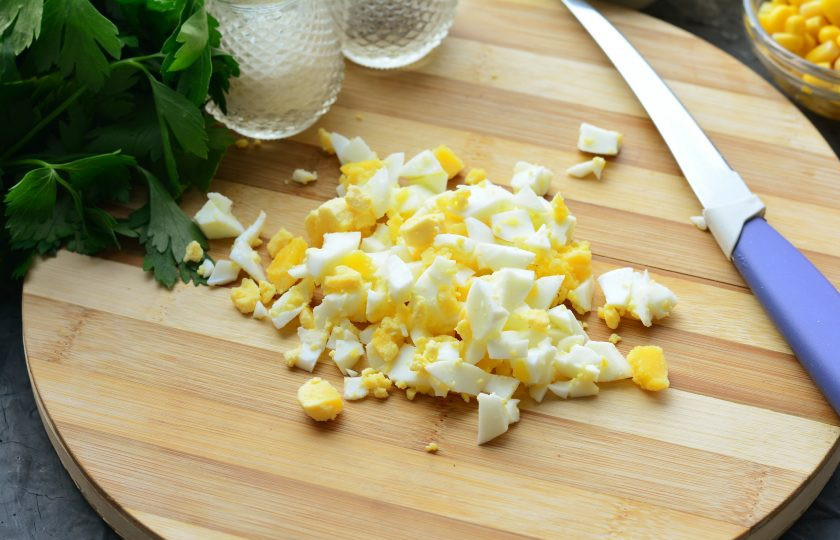 1. Этап. Салат с копченым мясом и кукурузой: Нарежьте кубиками сваренные вкрутую яйца.