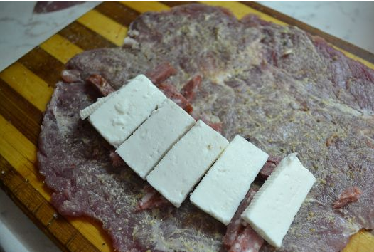 1. Этап. Свинина, фаршированная грибами и сыром: 2. Выкладываем начинку - кусочки колбасы, половина измельченных грибов, и сверху - толстые кусочки брынзы. Заворачиваем рулет и срепляем зубочистками.