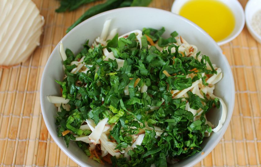 1. Этап. Салат с колбасным сыром и морковью: Насыпаем в салат порезанный шпинат.