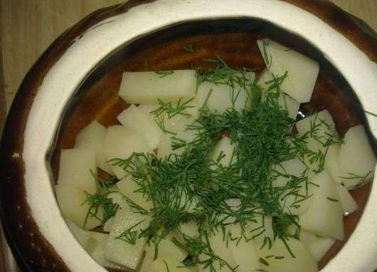 1. Этап. Жульен в горшочках с картошкой: Очистите и вымойте картофель, обсушите его, нарежьте клубни кубиками. Смажьте горшочки растительным маслом и выложите в них нарезанный картофель. Затем присыпьте его рубленым укропом.
